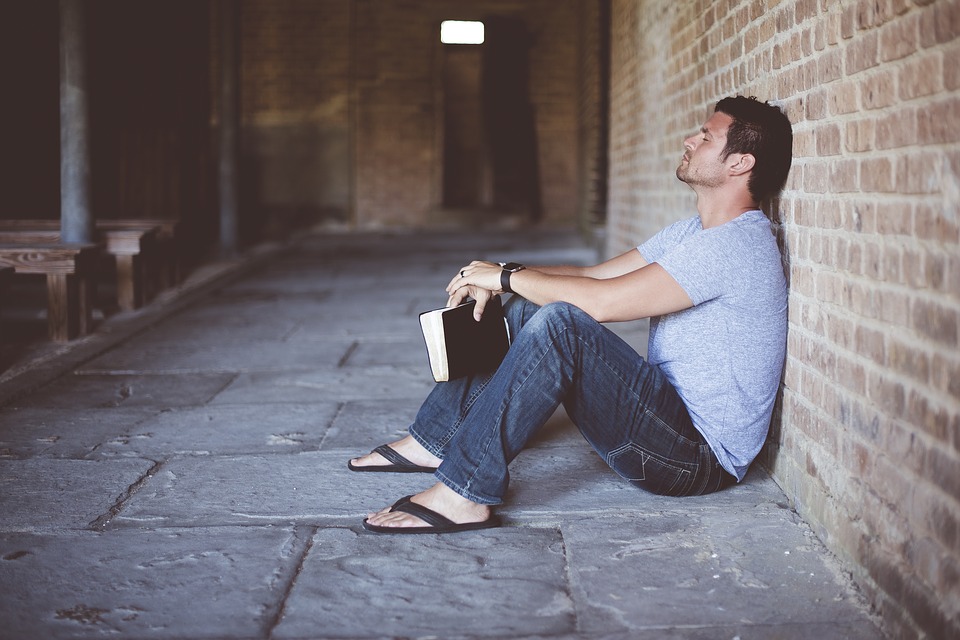 man sits alone against a brick wall
